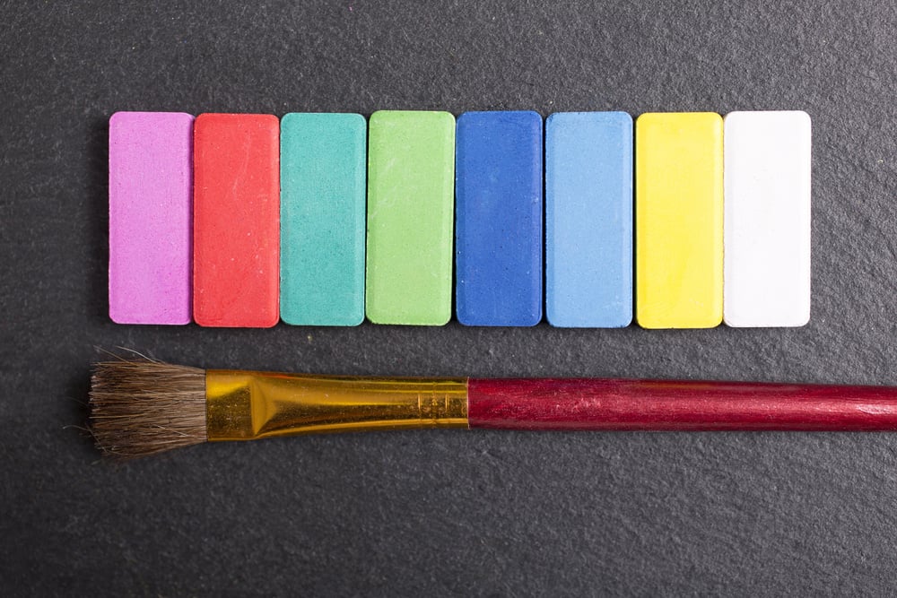 Colourful paint palette selection on a black slate surface with brushes